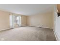 Spacious living room with neutral paint, plush carpet and natural light from a window with sheer curtains at 5852 Long Ridge Pl, Indianapolis, IN 46221