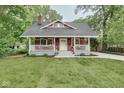Quaint home with a welcoming front porch, lush lawn, and a picturesque, tree-lined backdrop at 625 E 57Th St, Indianapolis, IN 46220