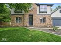 Close up view of a brick home's front entrance and garage, surrounded by a green lawn and small garden at 6396 Granny Smith Ln, Avon, IN 46123
