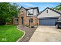 A brick home with an attached two-car garage surrounded by a well-kept lawn and minimal landscaping at 6396 Granny Smith Ln, Avon, IN 46123
