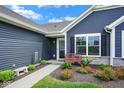 Charming home entrance featuring a red bench and lovely flowerbeds at 7184 Lillian Pl, Cumberland, IN 46229