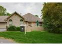 Brick home featuring a well-manicured lawn and garden area, complemented by mature trees and a 'For Sale' sign at 7545 Briarstone Dr, Indianapolis, IN 46227