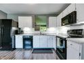 Modern kitchen featuring white cabinets, black appliances, subway tile backsplash, and wood grain vinyl flooring at 7942 Dillon Pl, Indianapolis, IN 46236