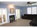 Carpeted living room with fireplace, ceiling fan, and natural light from the windows and glass panel doors at 8519 Frosty Rose Dr, Avon, IN 46123
