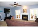 View of the living room with a fireplace, ceiling fan, and blue walls with a dark brown sofa at 8519 Frosty Rose Dr, Avon, IN 46123