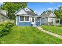 Quaint home features an inviting front porch, well-maintained lawn and mature trees at 938 N Tuxedo St, Indianapolis, IN 46201