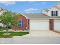 Two-car garage with brick accents and vinyl siding, set against a blue sky backdrop at 9682 Angelica Dr, Noblesville, IN 46060