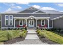 Charming front porch with red chairs, white columns, double doors, and manicured landscaping at 10655 E 200 S, Zionsville, IN 46077
