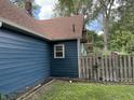 View of the side of a blue house with an external spiral staircase, a fenced yard, and leafy trees at 1206 Mcdougal St, Indianapolis, IN 46203