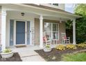 Inviting covered front porch features white columns, rocking chairs, decorative pillows and lush landscaping at 15409 Heath Cir, Westfield, IN 46074