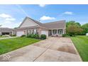 Well-maintained brick home with a green lawn, garages, and a charming front porch at 1905 Persimmon Grove Dr, Indianapolis, IN 46234