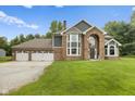 Beautiful home with brick and gray siding, arched entry, three-car garage, and mature trees at 2871 Mullinix Rd, Greenwood, IN 46143