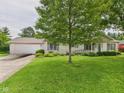 Ranch-style home with attached garage, well-manicured lawn, and garden beds full of colorful flowers at 3004 N Timber Ln, Muncie, IN 47304