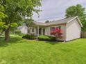 Charming ranch-style home with a covered porch, landscaped garden beds, and well-manicured lawn at 3004 N Timber Ln, Muncie, IN 47304