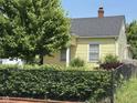 Yellow home with a dark roof, partially hidden by a black fence and mature trees at 407 N Alton Ave, Indianapolis, IN 46222