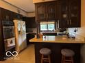 Functional kitchen featuring dark wood cabinets and a breakfast bar at 624 S High School Rd, Indianapolis, IN 46241