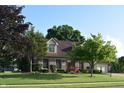 Traditional brick home with dormer windows and a well-manicured lawn with mature trees at 1065 Lakewood South Dr, Brownsburg, IN 46112