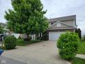 Exterior shot featuring a large driveway leading to a house with brick and tan siding at 11070 Long Lake Ln, Fishers, IN 46037