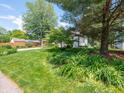 Landscaped front yard with lush green lawn and flowering plants in front of a single Gathering house at 1325 Countryside Ln, Indianapolis, IN 46231