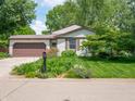 Charming home featuring a well-manicured front lawn, colorful flowers, and a large, two car garage at 1325 Countryside Ln, Indianapolis, IN 46231