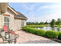 Relaxing outdoor patio with pond view, stone pavers, with decorative bushes and a black metal table at 13807 Rue Fontaine Ln, McCordsville, IN 46055