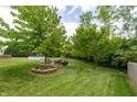Grassy backyard featuring mature trees and a circular fire pit with chairs for entertaining at 2096 Whitetail Ct, Avon, IN 46123
