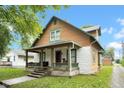 A side view of a two-story home showcasing a covered front porch, yard, and charming architectural details at 31 S Hinman St, Columbus, IN 47201