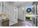 Bright foyer with hardwood floors, white staircase, and open front door at 321 4Th E Ct, Carmel, IN 46033