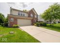 Inviting two-story home features a brick facade, attached garage, and manicured front yard at 5883 Sandalwood Dr, Carmel, IN 46033