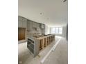 Open-concept kitchen with gray cabinets, an island being constructed, and large windows at 7317 Bayview Run, McCordsville, IN 46055