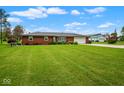 A well kept lawn fronts this brick home, complemented by mature landscaping and a two-car garage at 7447 S 25 E, Pendleton, IN 46064