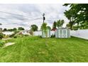 Manicured backyard with a storage shed, a garden, and a white fence at 121 Mulberry Dr, Chesterfield, IN 46017