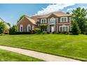 Charming brick house featuring a well-maintained lawn, professional landscaping, and inviting curb appeal at 14149 Ledgewood Way, Carmel, IN 46032