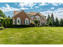 Stunning two-story brick home with a lush green lawn and mature trees at 14149 Ledgewood Way, Carmel, IN 46032