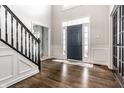 Elegant foyer with dark wood floors, paneled walls, and staircase with black wrought iron railing at 14149 Ledgewood Way, Carmel, IN 46032