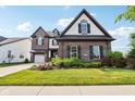 Two-story brick home with well-manicured lawn and garden featuring dark shutters and a three-car garage at 1521 Avondale Dr, Westfield, IN 46074
