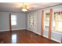 Spacious living room with polished hardwood floors, complemented by light grey walls, ceiling fan, and multiple windows at 1641 Winton Ave, Speedway, IN 46224