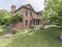 Red brick home with manicured landscaping, a balcony, and a side-entry garage in a lush setting at 20 Forrests Edge Ct, Indianapolis, IN 46227
