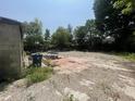A partially paved and graveled area with construction debris and overgrown vegetation at 4566 Melbourne Rd, Indianapolis, IN 46228