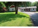 Landscaped front lawn with a mature tree leading up to a charming home with stone and red siding at 5654 Paradise Dr, Martinsville, IN 46151