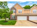 Attached garage and driveway of home; a beautiful landscaped tree in yard at 5677 Brownstone Dr # 5677, Indianapolis, IN 46220
