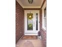Front door with sidelight, yellow flower wreath, welcome mat, and brick exterior at 6483 Royal Oakland Dr, Indianapolis, IN 46236