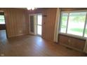 Large living room with hardwood floors, wood paneled walls, large windows and glass paned door at 6484 S State Road 39, Clayton, IN 46118