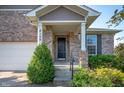 Inviting front porch with manicured shrubbery, columns, and a black front door at 8199 Sydney Ln, Avon, IN 46123