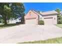 View of the home featuring an attached two car garage and a long driveway at 10760 Independence Way, Carmel, IN 46032