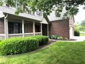Beautiful brick home featuring a charming covered front porch and a well-maintained lawn at 10760 Independence Way, Carmel, IN 46032