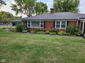 A classic brick ranch home showcases a modern metal roof and lush foundation landscaping at 1322 Greenway Dr, Anderson, IN 46011