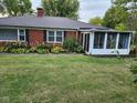 A quaint brick home featuring a sunroom addition and attractive foundation landscaping at 1322 Greenway Dr, Anderson, IN 46011