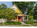 Charming yellow two-story home featuring a welcoming front porch, colorful red door and well-maintained landscaping at 224 N Pennsylvania St, Greenfield, IN 46140