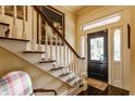 Elegant staircase with detailed white railings, complemented by classic decor and a view of the front entrance at 224 N Pennsylvania St, Greenfield, IN 46140